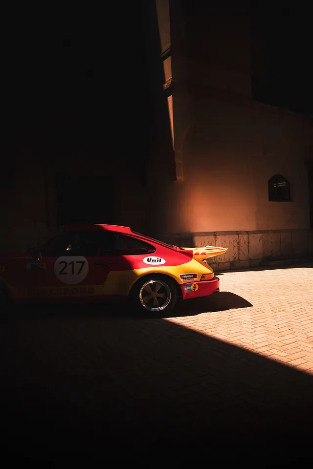 Porsche 911 racer in chiaroscuro courtyard, photographic, retro, warm