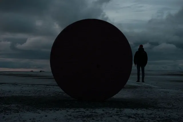 Human scale against monumental sphere, photographic, surreal, dark