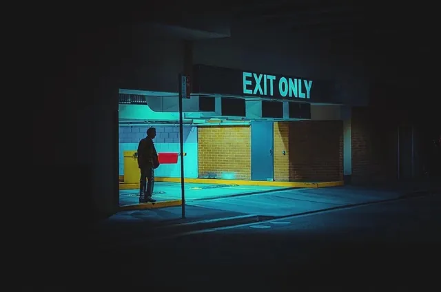 Neon-lit figure under cyan EXIT ONLY sign in moody urban alley, photographic, moody, dark