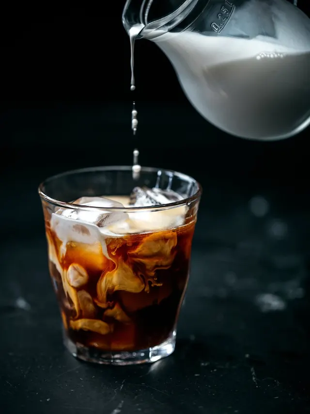 Product shot of liquid pour into cola glass, photographic, clean, dark