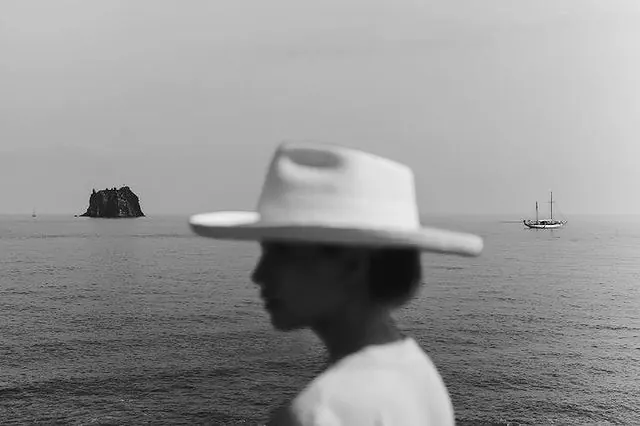 Man in white fedora overlooking moody seascape, photographic, monochrome, monochrome