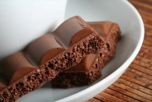 Chocolate-dipped wafer sticks in white bowl, photographic, warm