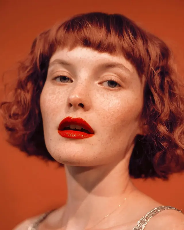 Portrait photography with warm orange background and bold red lips, photographic, bold, warm