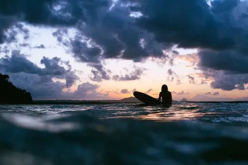 Surfer silhouette at dramatic sunset, photographic, dramatic, warm