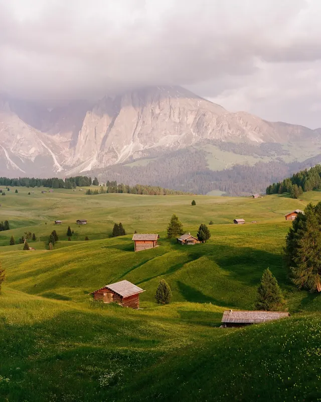 Alpine mountain valley with wooden huts at sunset, photographic, earthy