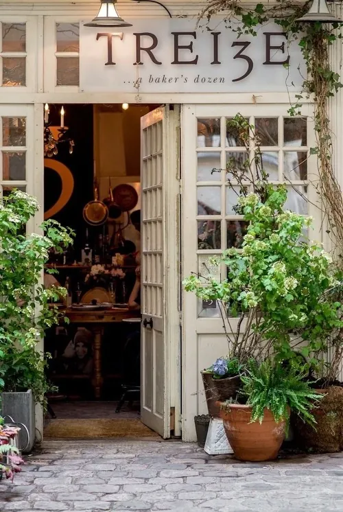 Treize bakery storefront with open doors and potted plants, minimal, photographic, warm