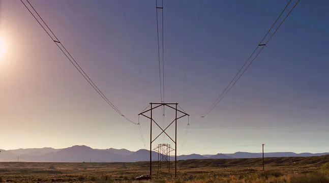 Desert landscape with silhouetted power lines at dusk, photographic, minimal, muted