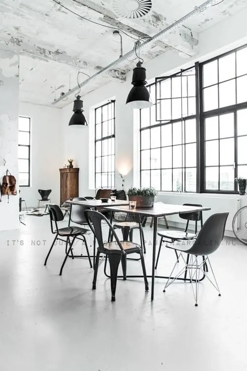 Industrial loft workspace with black pendants and mixed chairs, minimal, photographic, light
