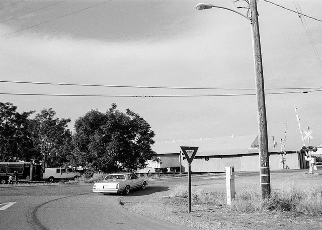 Vintage sedan turning past yield sign in monochrome street scene, monochrome, photographic, monochrome