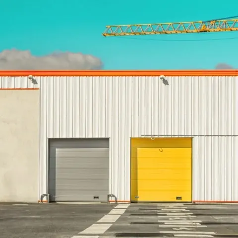 Industrial warehouse facade with yellow door, photographic, minimal, vibrant
