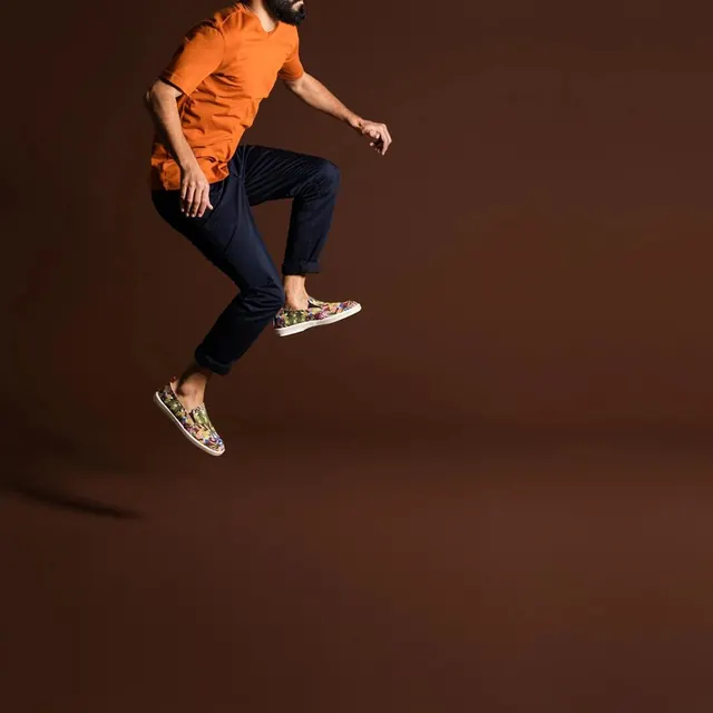 Person in orange shirt jumping mid-motion, photographic, playful, warm