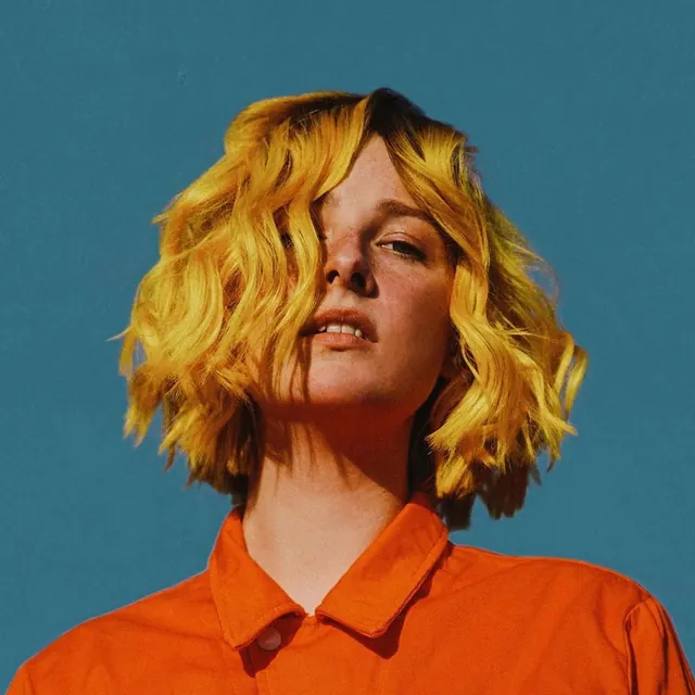 Portrait with yellow hair and orange shirt, photographic, bold, vibrant