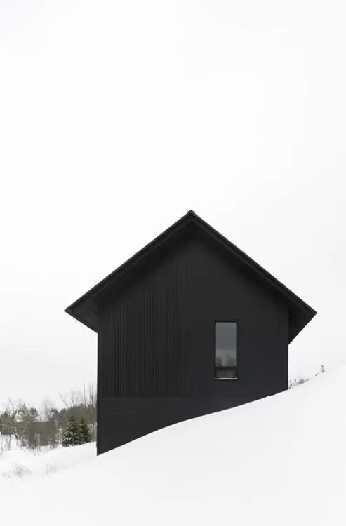 Modern black house rotated on snowy landscape, minimal, architectural, dark