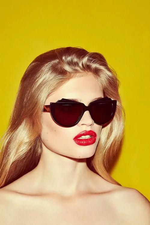 Portrait with oversized sunglasses against vibrant yellow, photographic, bold, vibrant