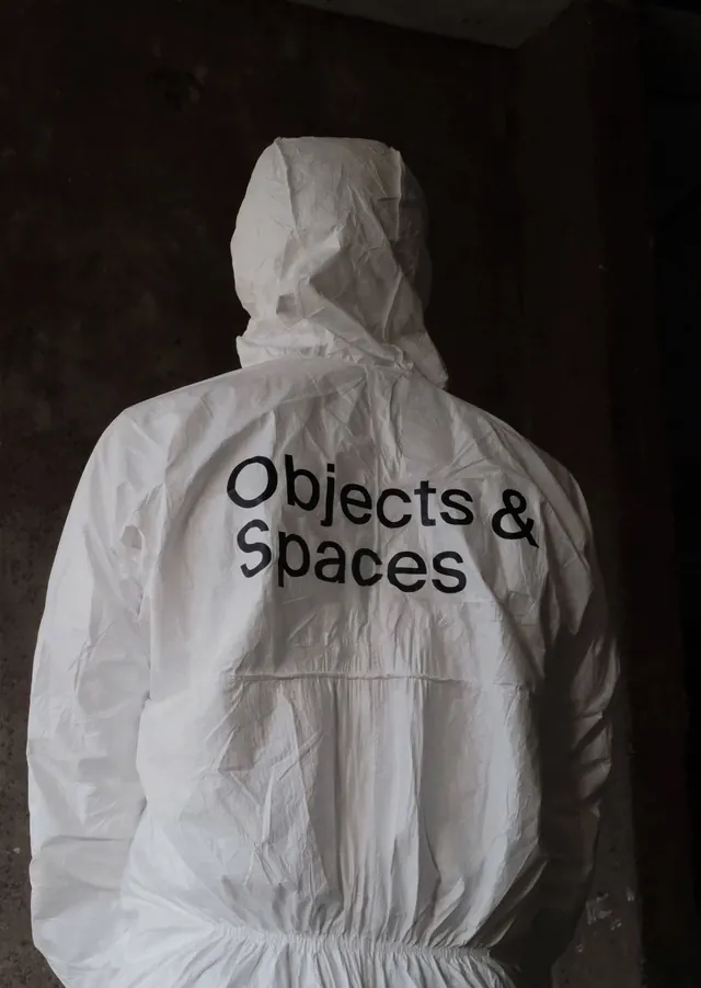 White jacket with minimalist text against dark background, photographic, minimal, monochrome