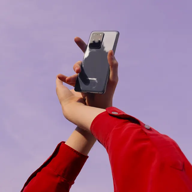 Samsung phone held against lavender background, photographic, playful, warm