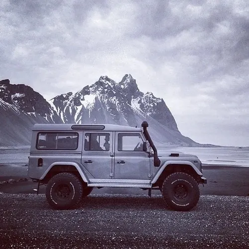 Land Rover on remote black-sand beach, photographic, minimalist, cool