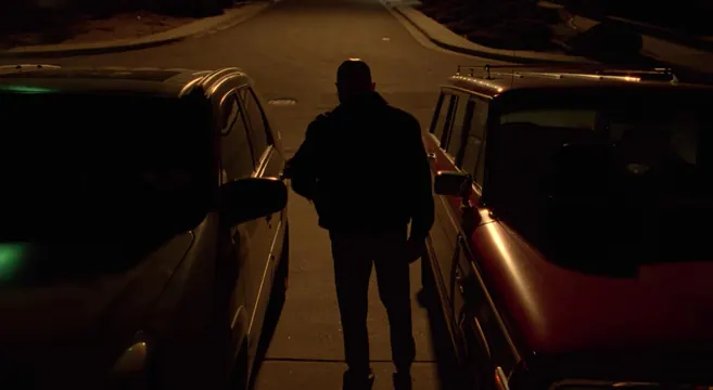 Nighttime figure between lit cars, photographic, dark-mode, dark
