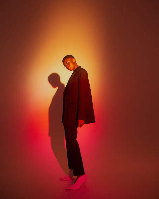 Figure portrait with dramatic warm-to-cool gradient backdrop, photographic, editorial, vibrant