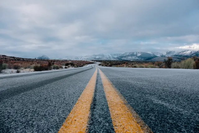 Desert road with snow-capped mountains, photographic, minimal, cool