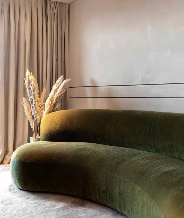 Curved green sofa with botanical styling, minimalist, photographic, warm