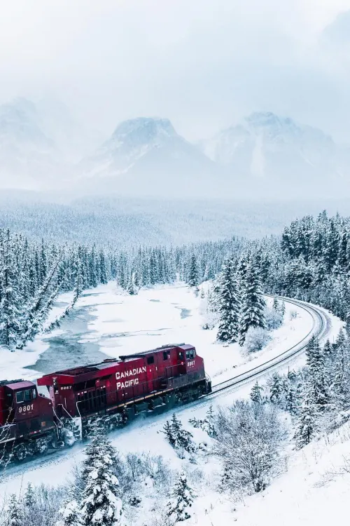 Canadian Pacific freight train in snowy mountain landscape, photographic, editorial, dark