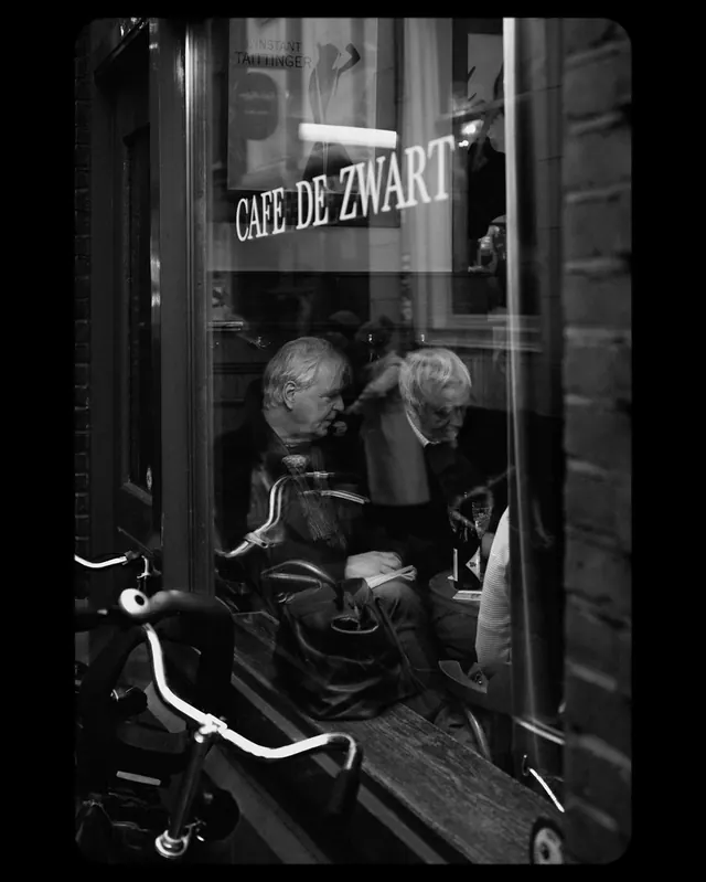 Cafe storefront with person in Amsterdam, photographic, dark-mode, dark