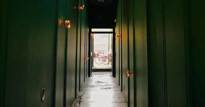 Green paneled corridor with daylight doorway, minimal, photographic, dark