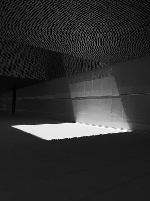 Sunlit rectangle in a dark architectural corridor, photographic, minimal, monochrome
