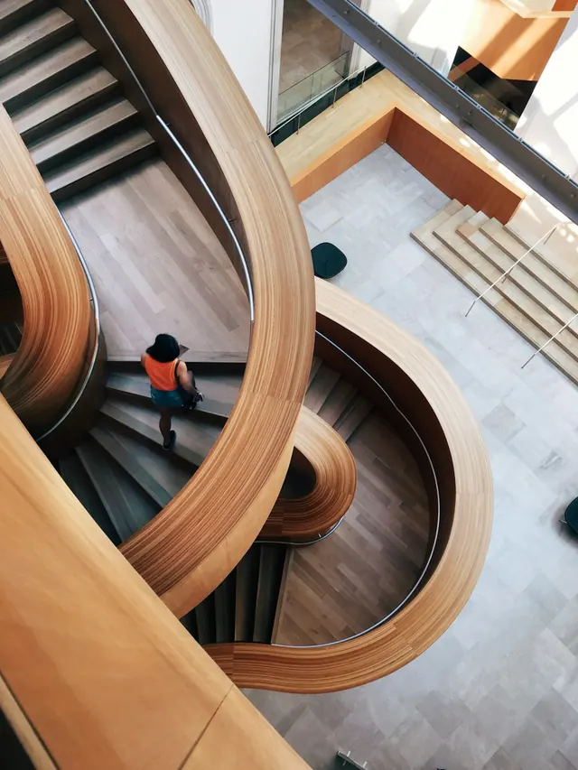 Wooden spiral staircase with light from above, overhead perspective, photographic, minimal, warm