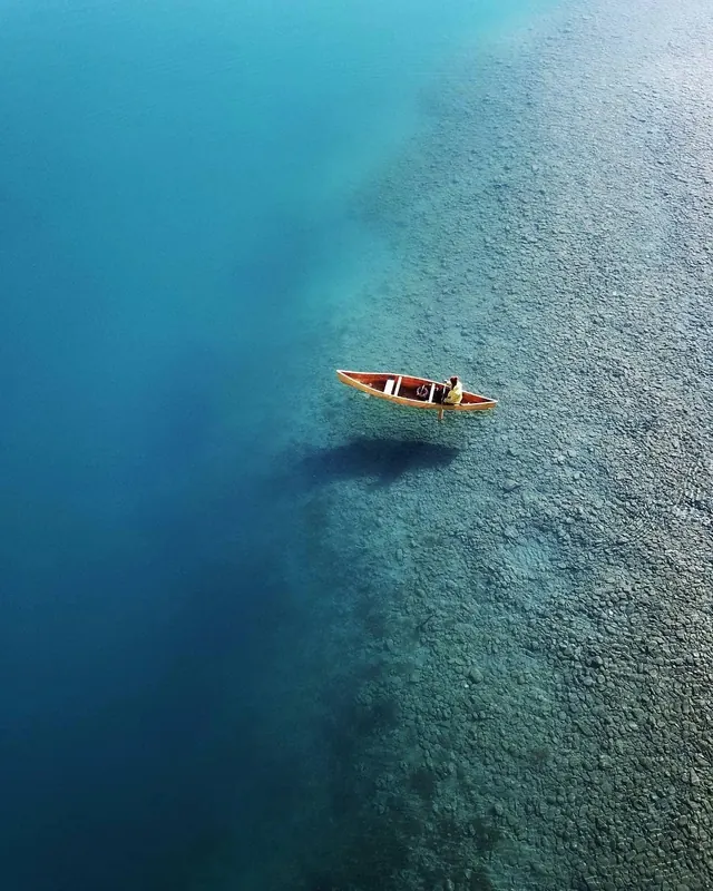 Aerial photograph of wooden boat in turquoise water, photographic, minimal, cool