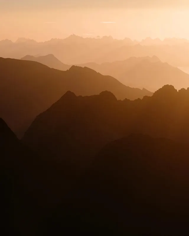 Mountain silhouettes at sunset, photographic, minimalist, warm
