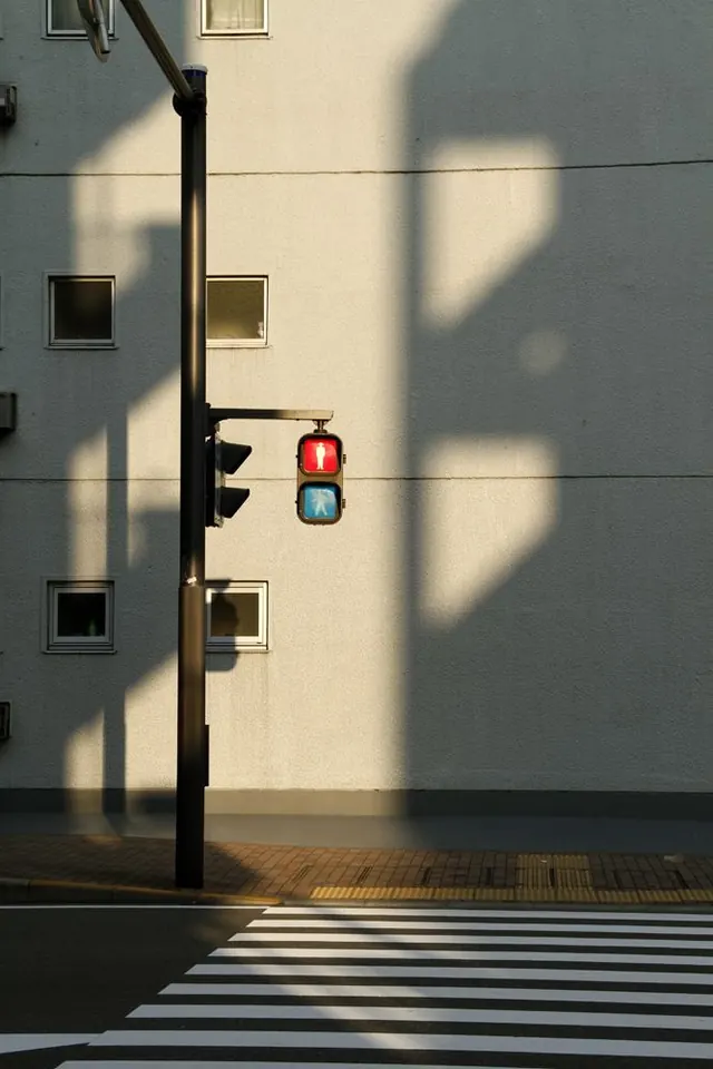 Traffic light against urban architecture and shadows, photographic, minimalist, light