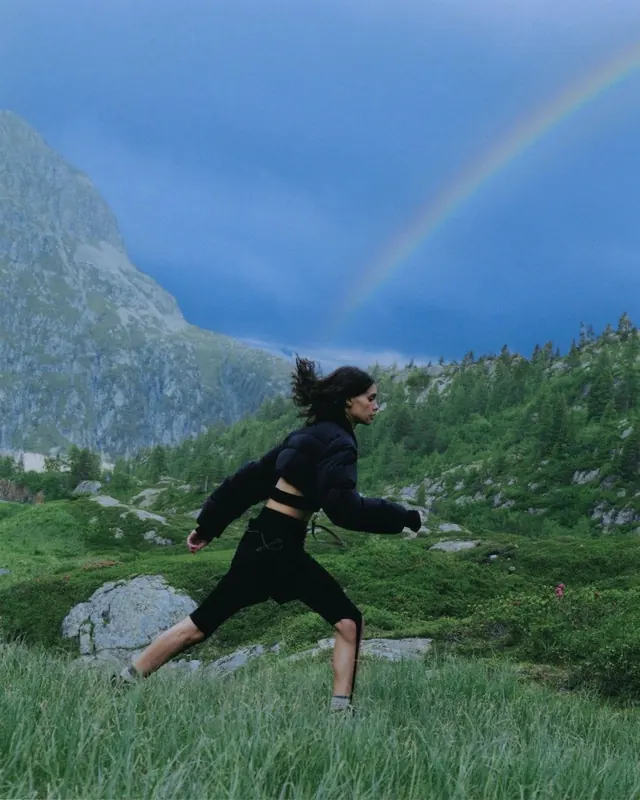 Woman jumping in mountain landscape with rainbow, photographic, cool