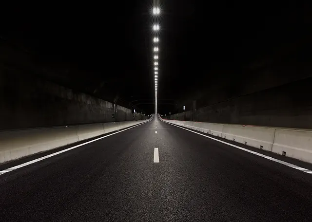 Nighttime highway tunnel with vertical light column, photographic, technical, dark