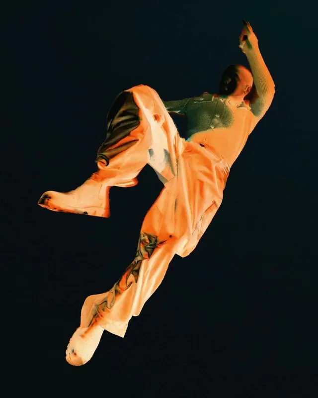 Dancer in orange against dark background, photographic, minimalist, warm