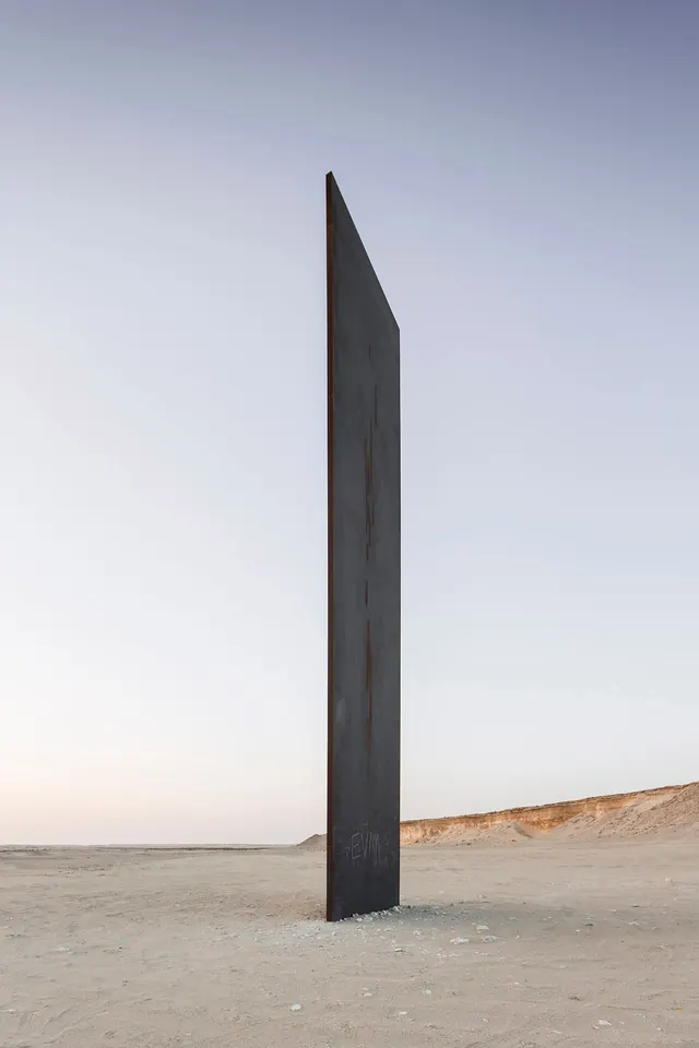Monolithic concrete structure on beach, minimal, brutalist, dark