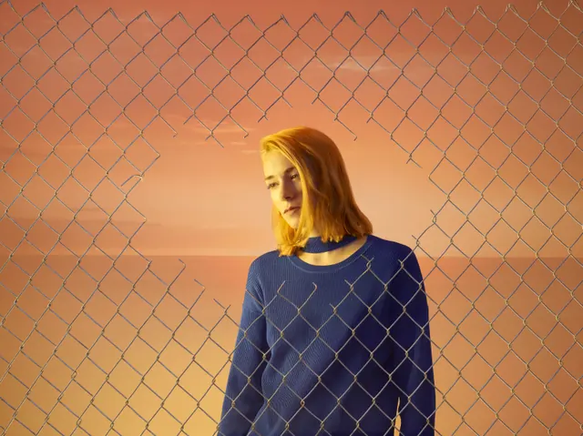 Portrait with chainlink fence backlight, photographic, editorial, warm