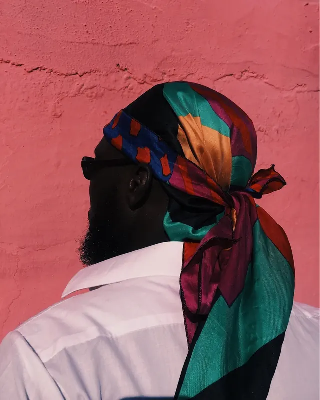 Portrait with colorful headwrap and pink background, photographic, bold, dark