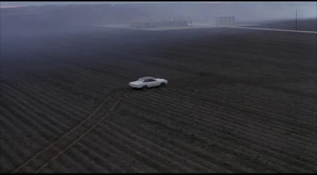 Lone car on empty industrial field, photographic, minimalist, dark