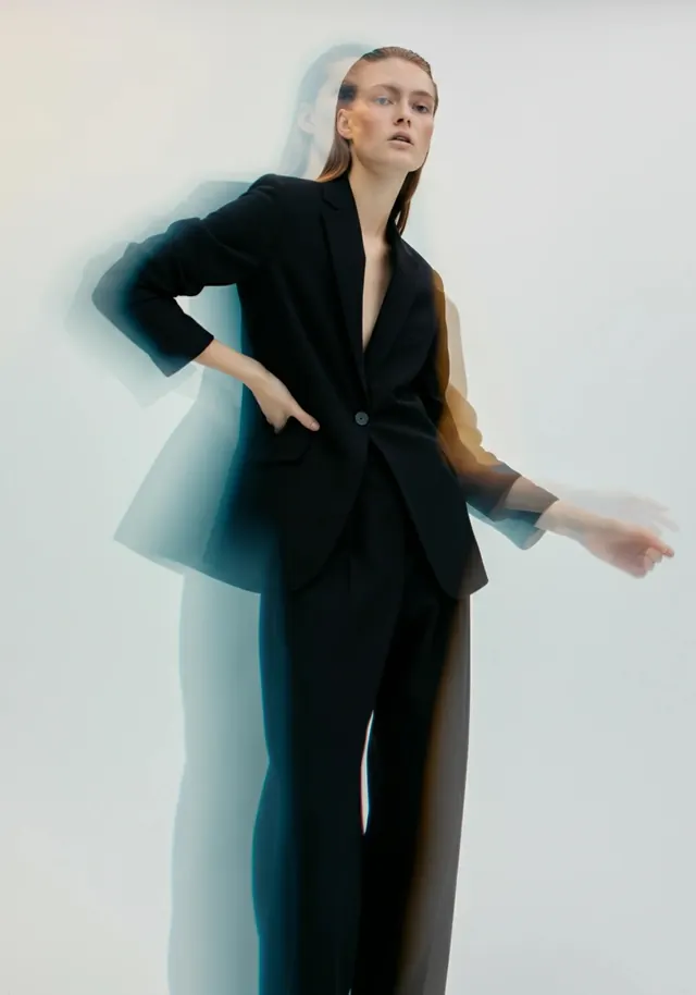 Figure in black blazer with cool-toned shadow effect, photographic, minimal, dark