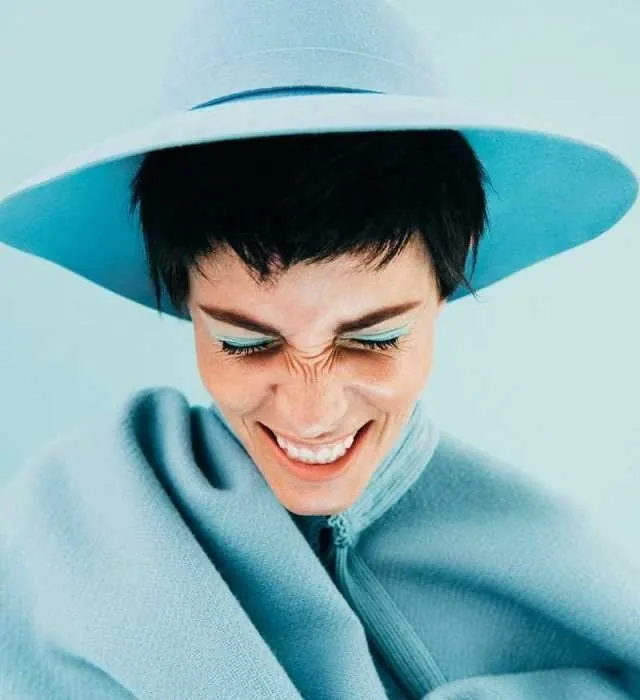 Woman with wide-brimmed hat and teal eyeshadow, photographic, editorial, cool