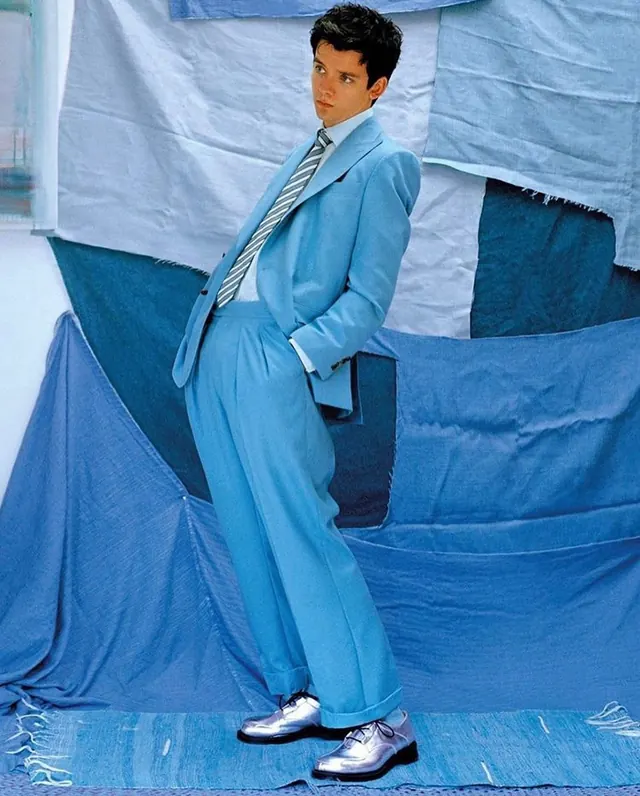 Man in blue suit with fabric backdrop, photographic, editorial, cool