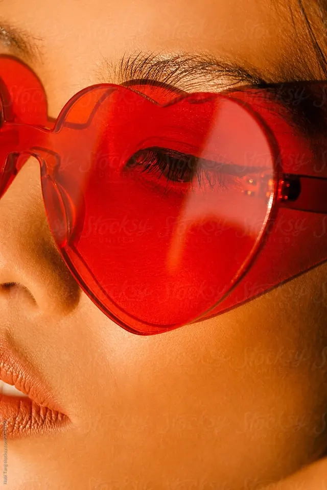 Heart-shaped red glasses portrait, playful, photographic, warm