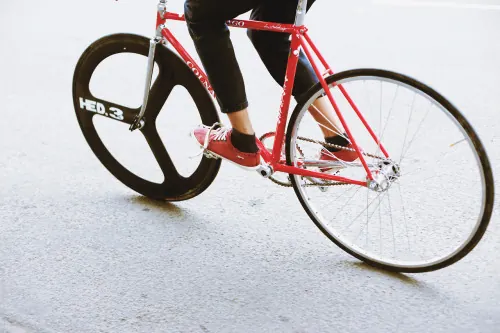 Red fixed-gear bike with black tri-spoke wheel, minimalist, photographic, vibrant