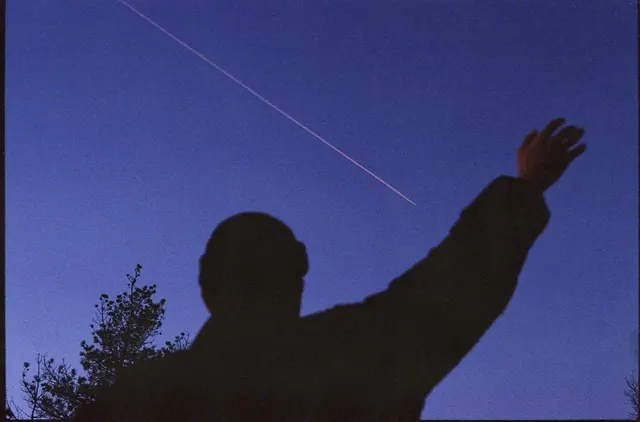 Silhouette figure reaching toward starlight, photographic, minimal, dark