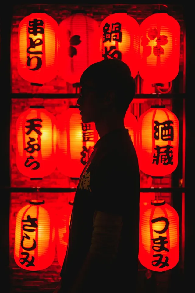 Silhouetted figure with red lanterns, photographic, dark-mode, dark