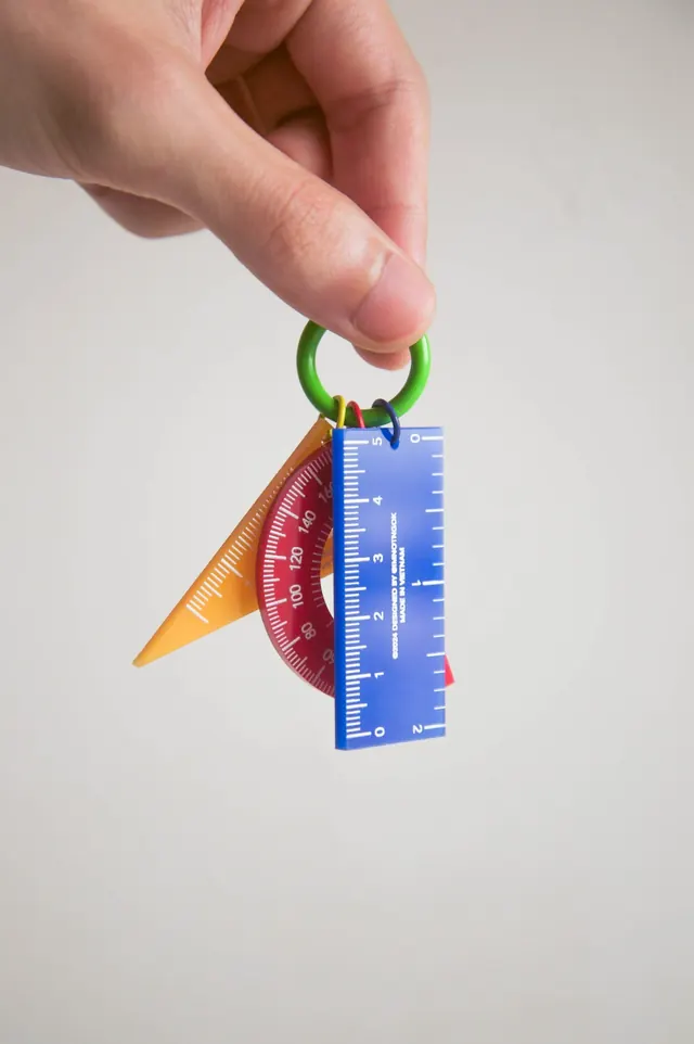 Product photography: compact multi-tool keychain with measurement scales, minimal, photographic, warm